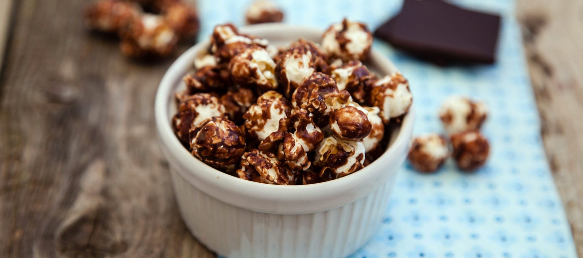 Chocolate covered popcorn in a white bowl on wooden table